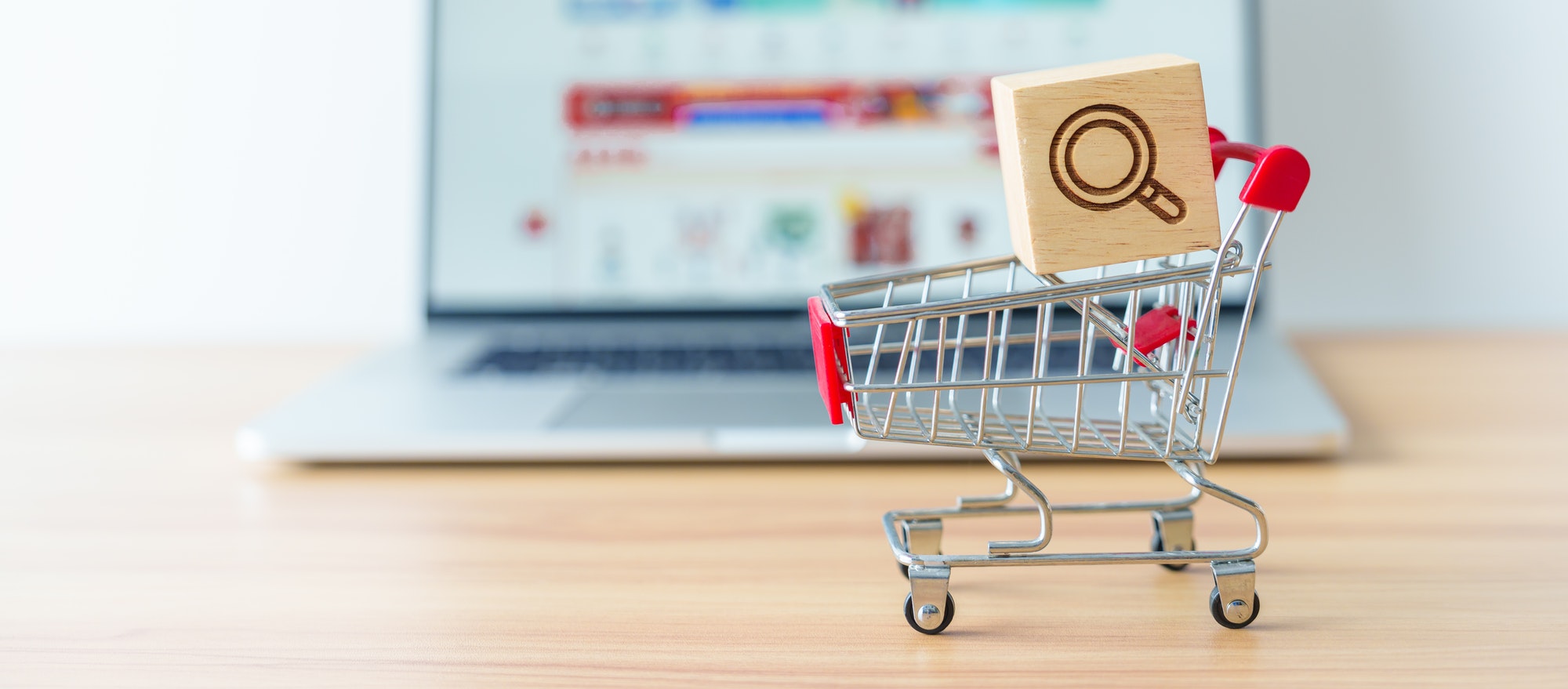 Shopping cart with Magnifying icon block and laptop computer